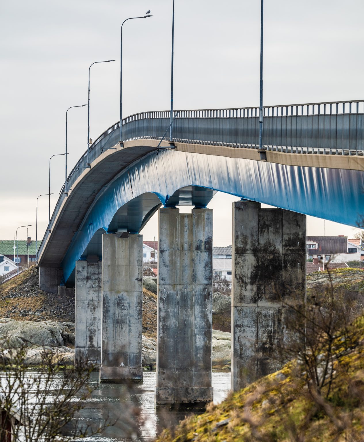 Bro i Göteborg, som leder över vatten med betongpelare och vägtrafik, omgiven av kustlandskap och bebyggelse