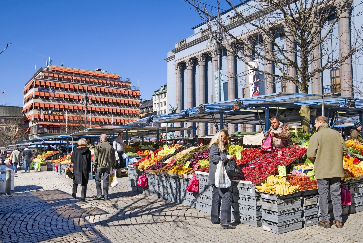 Torghandel på Hötorget i Stockholm med frukt- och grönsaksstånd samt människor