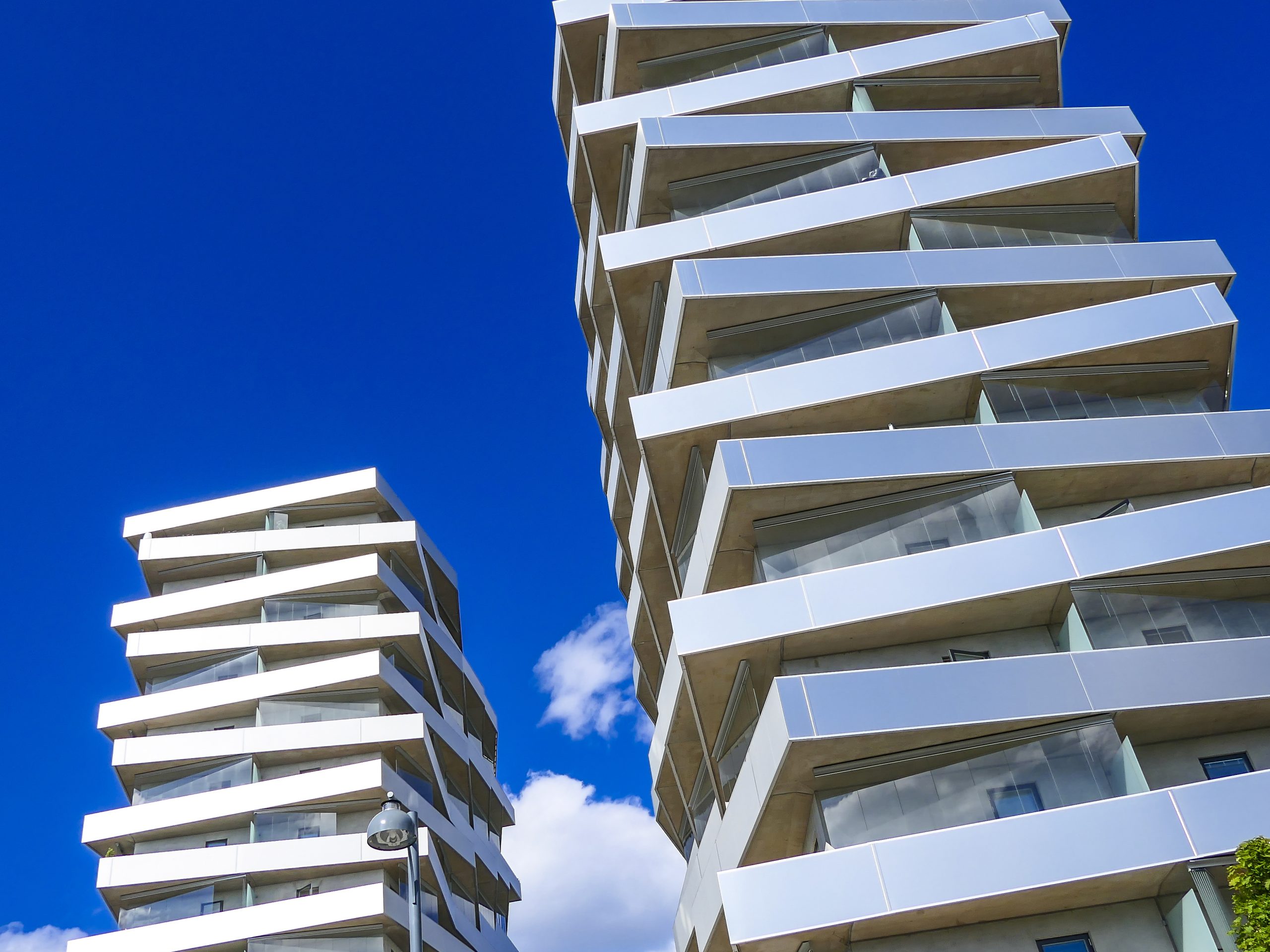 Moderna höga bostadshus med samtida arkitektur mot blå himmel. Bilden används för att illustrera rapporten ”En stad att se upp till” från Stockholms Handelskammare.