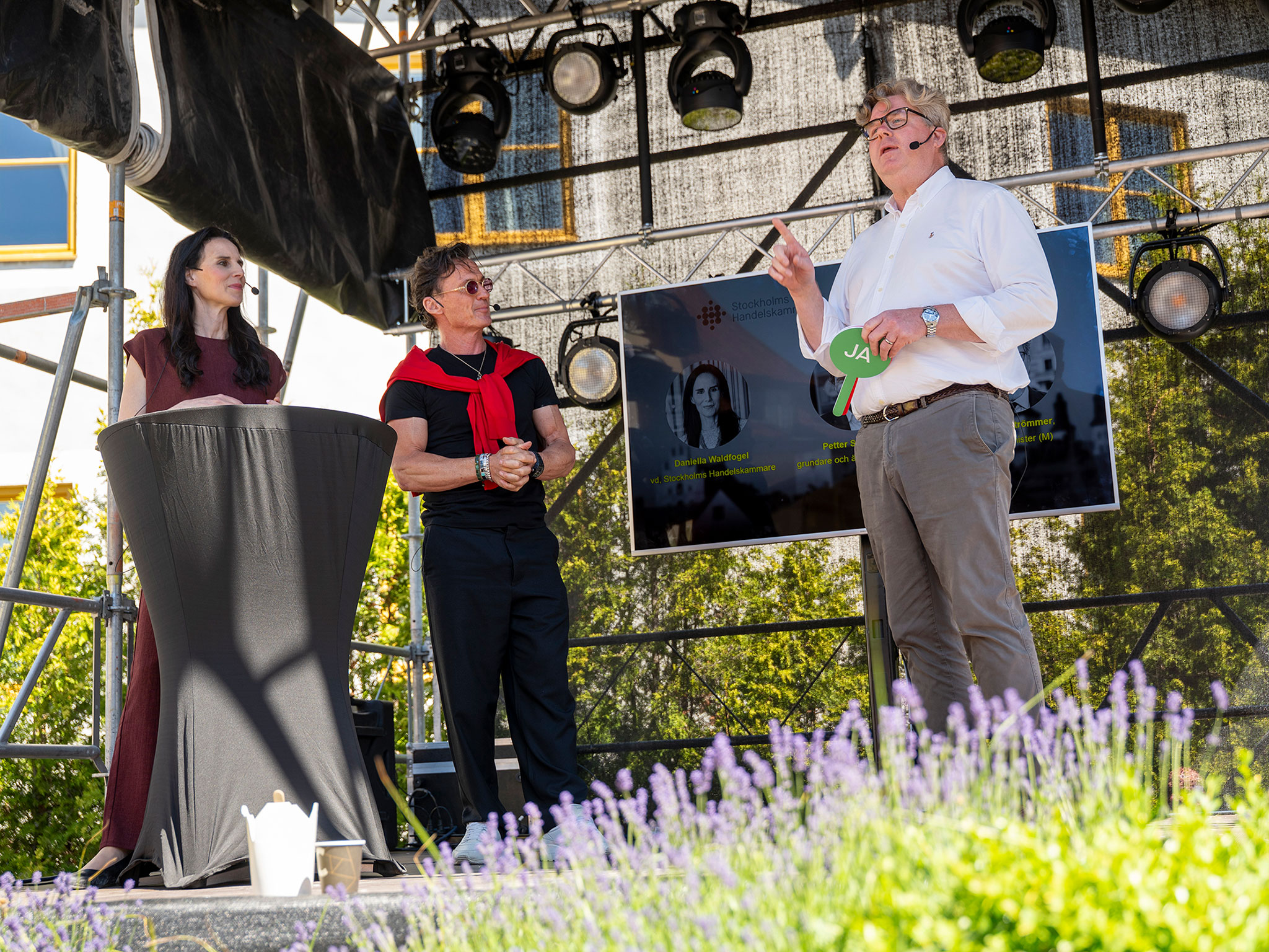 Daniella Waldfogel, vd på Stockholms Handelskammare, Petter Stordalen, grundare och ägare av Strawberry Group, samt justitieminister Gunnar Strömmer (M) på scen under Stockholms Handelskammares och Strawberrys lunchmingel under Almedalsveckan 2026.
