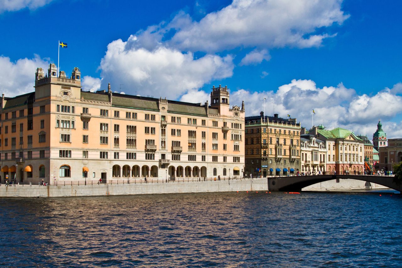 Rosenbad i Stockholm vid Strömmen under blå himmel med svenska flaggan på taket.