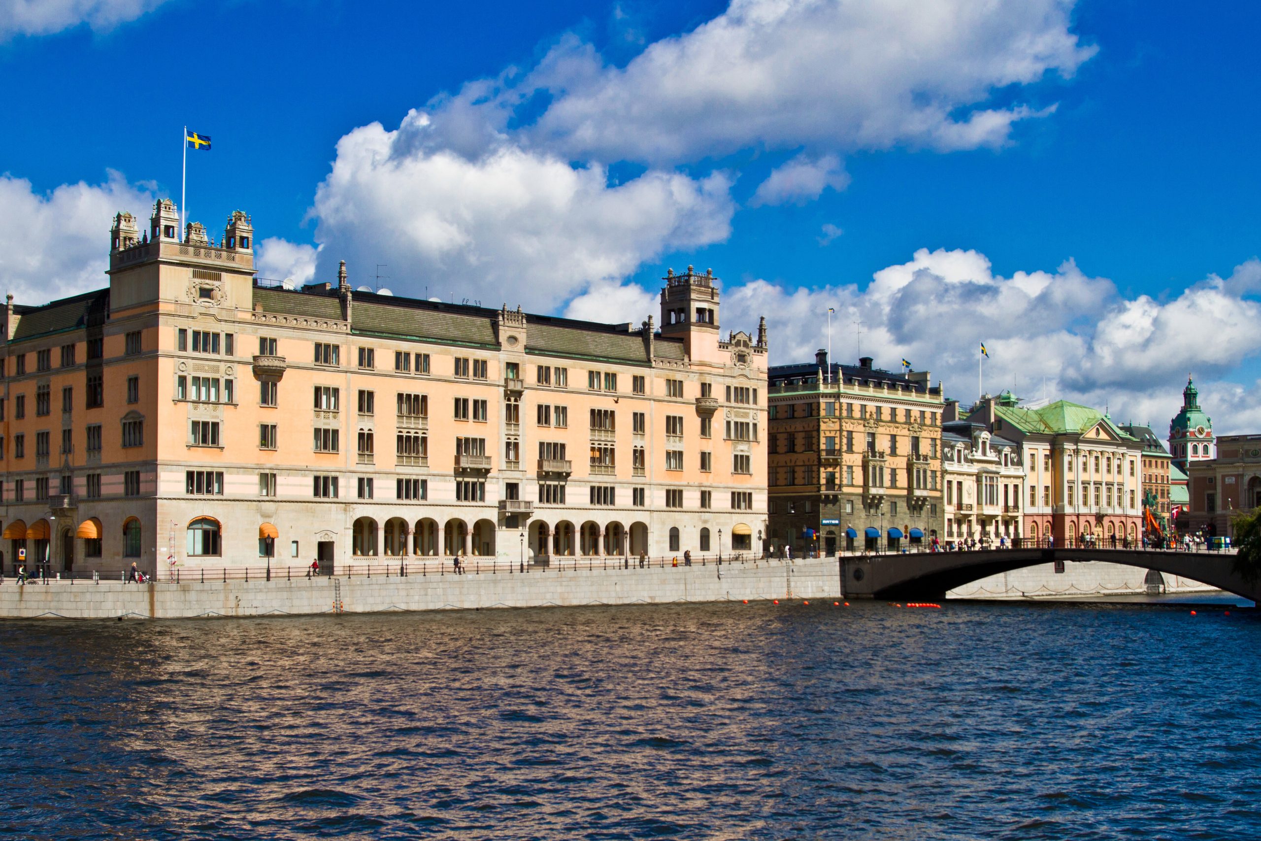 Rosenbad i Stockholm vid Strömmen under blå himmel med svenska flaggan på taket.